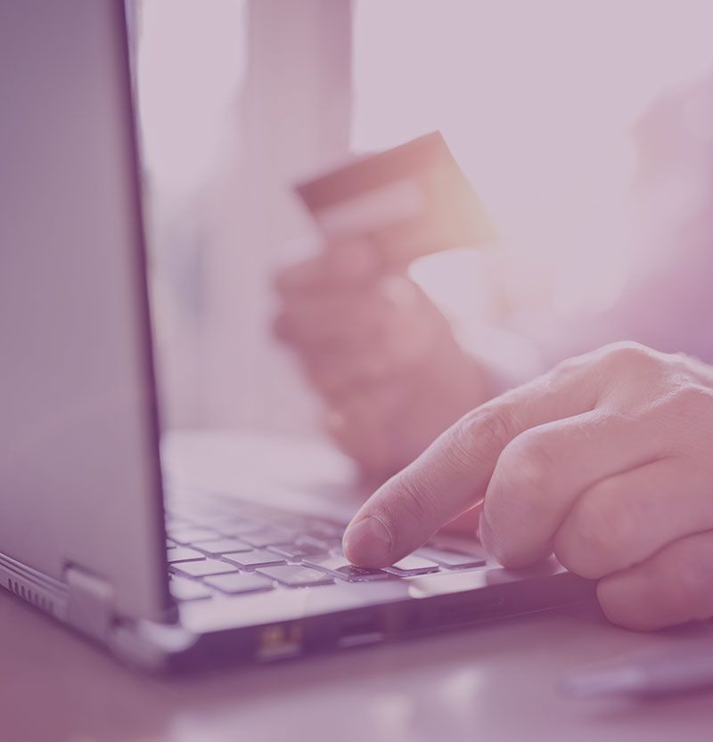 Hand typing on laptop with credit card for online payment in soft pink lighting - accounting services for e-commerce creatives and online business professionals