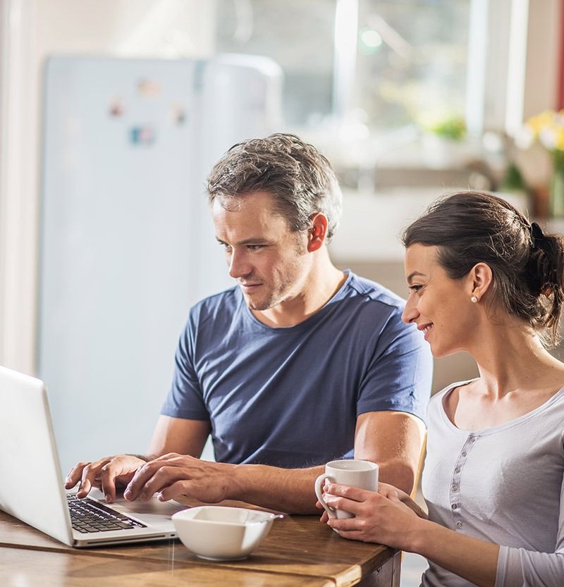 A couple sitting at a table, reviewing something on a laptop, symbolizing the partnership and collaboration that creative businesses need when managing their financial affairs with expert accounting services.